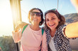 © olezzo - An elderly beautiful woman and her adult daughter travel together, do selfie on a mobile phone in the cockpit of a funicular during a summer holiday at sea
