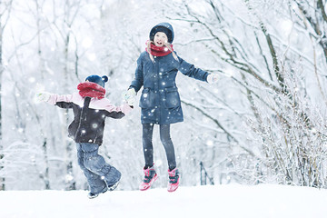 Wall Mural - cheerful happy little girl on winter walk / little girl smiles and laughs in  snow, plays winter for a walk. The concept of  happy childhood. Warm sportswear down jacket, mittens, children's shoes