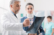 © StockPhotoPro - Doctor examining a young female patient's x-ray, she is wearing a cervical collar and having a serious neck injury