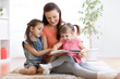 © Oksana Kuzmina - pretty mother reading book to her daughters