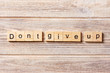 © sosiukin - Dont give up word written on wood block. Dont give up text on table, concept