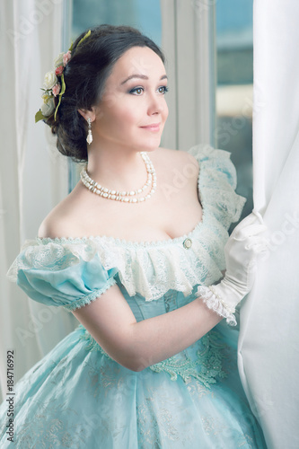 Photographie Elegant woman in historical dress and in jewelry waiting for friends at the ball