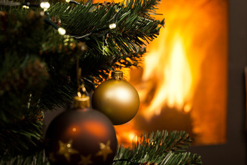 decorations on christmas tree and fire burning in fireplace in the background