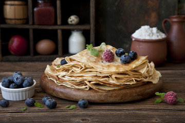 Baked fresh pancakes on a vintage wooden plate with fresh berries. Close-up, selective focus, shallow depth of field