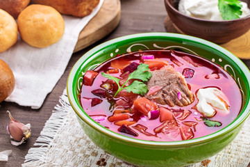 Wall Mural - Bowl of borscht on table. Sour soup with beetroots, cabbage and beef. Traditional Russian and Ukrainian dish. 