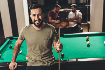young handsome caucasian man beside billiard table in bar with friends