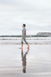 Hombre joven paseando por la playa en un día nublado 