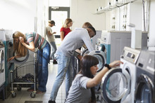 University Students Using Washing Machines At Campus Laundromat