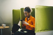 © Maskot - Mid adult businesswoman using smart phone while sitting on green chair at office