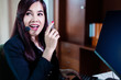 © whyframeshot - Smiling asian businesswoman using headset against elegane wooden interior room business ideas concept