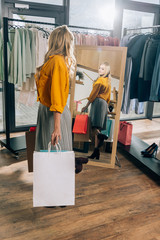 beautiful young woman looking at mirror in clothing store