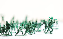 Many Green Army Plastic Toy Soldiers Organized On Top Of A White Surface And Background, Isolated, With Out Of Focus Plastic Soldiers In The Background