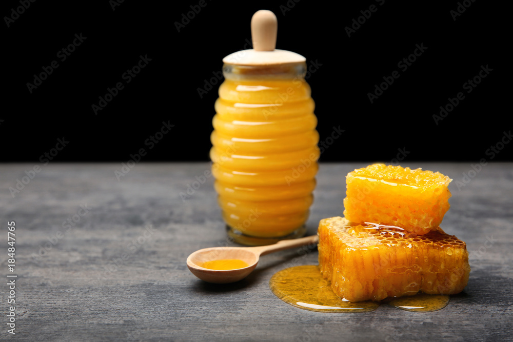 Fresh honeycombs and jar with honey on table