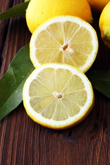 Wall Mural - Pile of lemons with leaves on brown wooden table