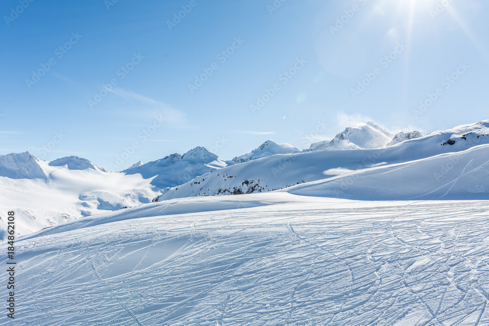 Off-piste ski slope with trace from skis and snowboards at sun winter day. Kavkaz mountains. - obrazy, fototapety, plakaty 