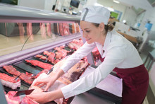 Happy Female Butcher In Meat Store Counter