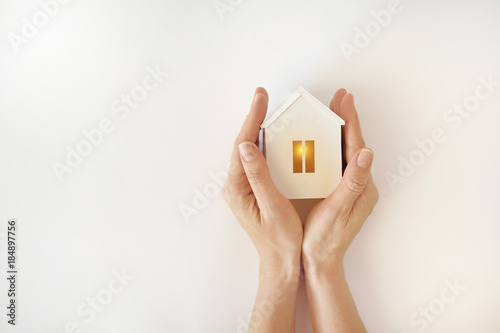 Fotografía The model of the White House with warm light inside in female hands on a white b