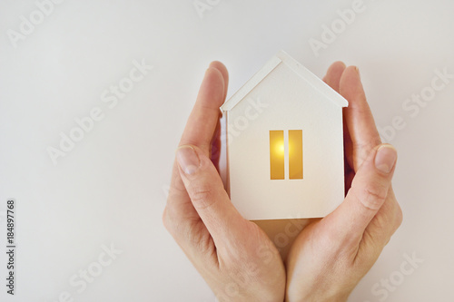 Fotografía The model of the White House with warm light inside in female hands on a white b