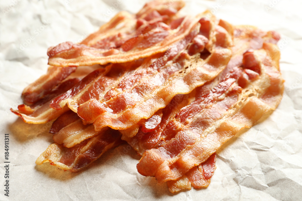 Cooked bacon rashers on parchment, closeup