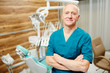 © pressmaster - Mature dentist in uniform crossing his arms on chest while looking at camera