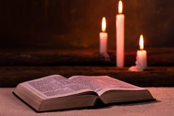 Bible and candle on a old oak wooden table.  Beautiful gold background.Religion concept.