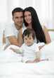 © ASDF - Portrait of a joyful family sitting on the bed at home