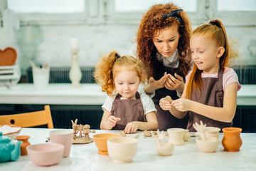 redhad Mother and two kid daughter at home molded from clay and play together