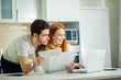 © alfa27 - Happy couple at home paying bills with laptop and looking screen