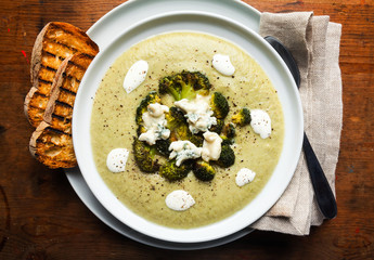 Wall Mural - broccoli cheese soup and fresh grilled bread with sour cream and black pepper with gorgonzola on wooden table