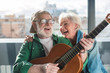© Yakobchuk Olena - Endless sunshine. Waist up portrait of laughing aged man and woman enjoying time together with musical instrument at home. Happy retirement concept