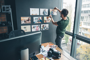 Aufkleber - Serious bearded man ornamenting wall by different images while standing in office. Labor and design concept