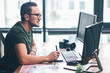 © Yakobchuk Olena - Side view orderly bearded retoucher working with graphic electronic tablet while situating at desk. Occupation concept