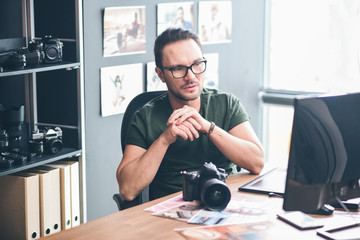 Aufkleber - Portrait of pensive bearded photographer looking at screen of computer while situating at desk. Job concept