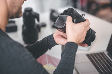 Aufkleber - Top view close up male hands holding digital device for taking photos. He looking at screen of it at desk. Image concept
