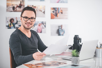 Aufkleber - Portrait of beaming bearded photographer having job with images while holding them in arms at table. Labor and hobby concept