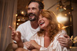 © Yakobchuk Olena - Look at that. Portrait of excited woman pointing finger forward and laughing. Man is hugging her with joy while sitting in bedroom