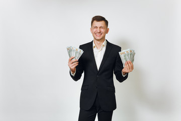 Young successful handsome rich business man in black suit holding wad of cash dollars isolated on white background for advertising. Concept of money, achievement, career and wealth in 25-30 years.