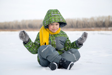 the boy sits on the ice on the lake