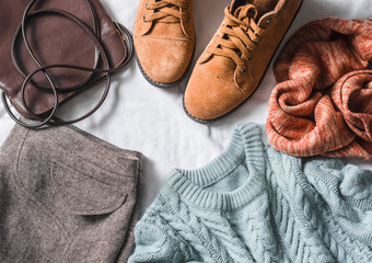 Women's clothing set - skirt, suede boots, sweater, scarf, leather  bag on a light background, top view. Winter, fall female clothing. Flat lay