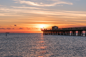 pink and orange morning skies over the ocean by the pier