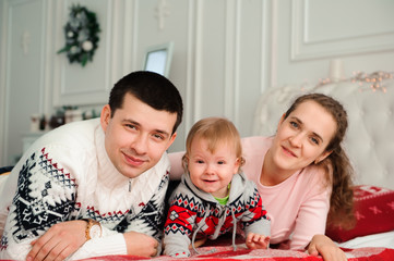 Happy smiling family with one year son near the Christmas background