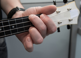 A man plays ukulele Detail of the Hand