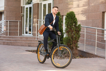 Wall Mural - Young handsome businessman riding bicycle outdoors