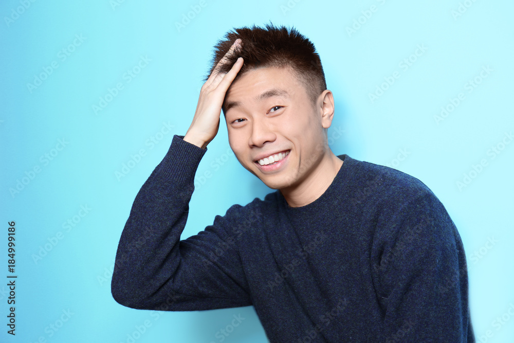 Portrait of young Asian man on color background