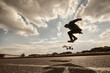 Youth, leisure, recreation, hobby, active lifestyle and extreme sports. Outdoor portrait of silhouette of teenage boy jumping high with skate in the air going to land on board while doing kick flip