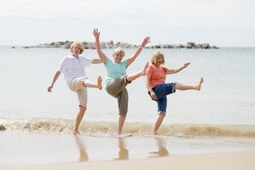 Canvas Print - group of three senior mature retired women on their 60s having fun enjoying together happy walking on the beach smiling playful