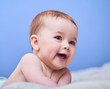 © Agave Studio - Portrait of a smiling crawling baby  over blue background. Space for text