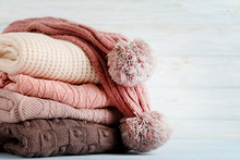 Stack Of Knitted Sweaters And Scarf On Wooden Table
