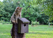 Kitty Cat sitting on top of birdhouse.  Domestic cat waiting, watching and hunting for birds in country outdoor setting.