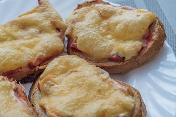 close-up of baked hot sandwiches with cheese and sausage on white plate